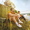 bild A woman and a man are sitting relaxed at a viewpoint overlooking a river and wooded hills.